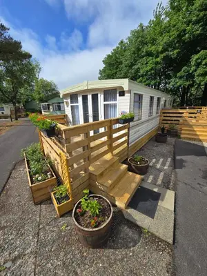 a house with a porch with potted plants on it at Woodlands Retreat Holiday Home in Ballantrae