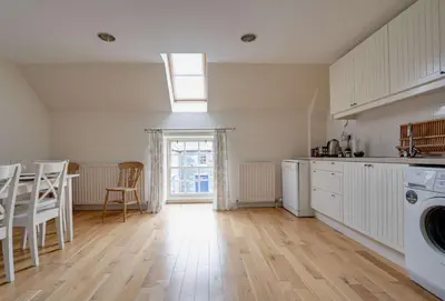 a kitchen with white cabinets and a washer and dryer at Penninghame Estate - Wallace Apartment in Challoch