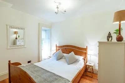 a bedroom with a bed with white sheets and a mirror at Penninghame Estate - Stewart Apartment in Challoch