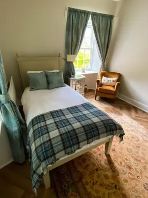 a bedroom with a bed and a window and a chair at Penninghame Estate- Gardeners Cottage in Challoch