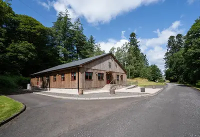 a large wooden building on the side of a road at Penninghame Estate - Earl's Library in Challoch