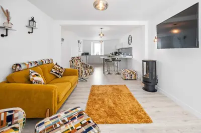 a living room with a yellow couch and a kitchen at Stunning 2BR Apt - Central High Street Location in Oban