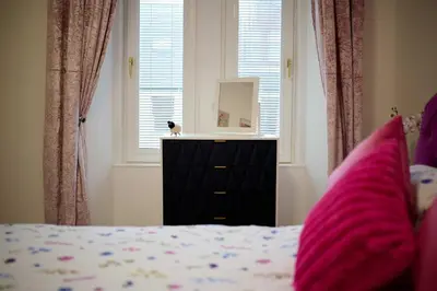 a bedroom with a bed and a dresser with a mirror at Stunning 2BR Apt - Central High Street Location in Oban