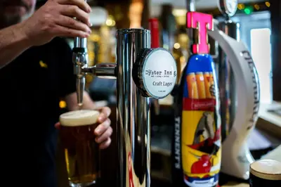 a person is making a glass of beer at Oyster Inn Connel in Oban