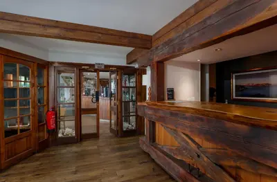 a bar in a room with wooden walls and wooden floors at Oyster Inn Connel in Oban