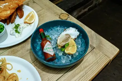 a blue bowl of food with a bottle of sauce at Oyster Inn Connel in Oban