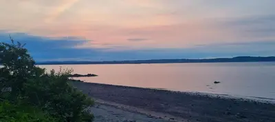 a view of a beach with the sun setting over the water at Thistle & Tide in Edinburgh