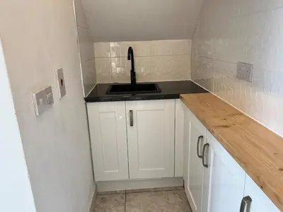 a small kitchen with a sink and white cabinets at Self-contained ground level cottage with hill view in Edinburgh