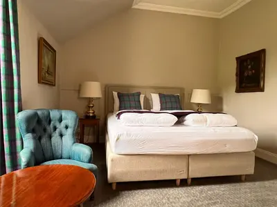 a bedroom with a bed and a blue chair at Kilfinan Hotel in Kilfinan