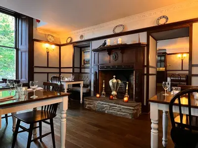 a restaurant with a fireplace and a table and chairs at Kilfinan Hotel in Kilfinan