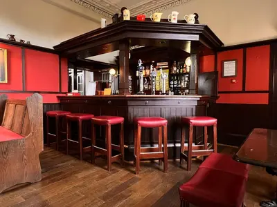 a bar with red walls and red stools at Kilfinan Hotel in Kilfinan