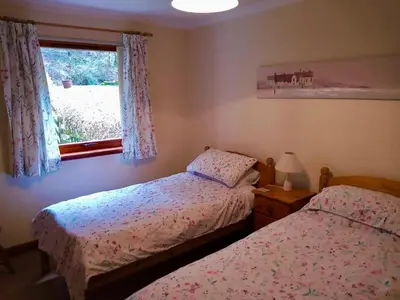 two beds in a bedroom with a window at Lochside Cottage Glencoe
