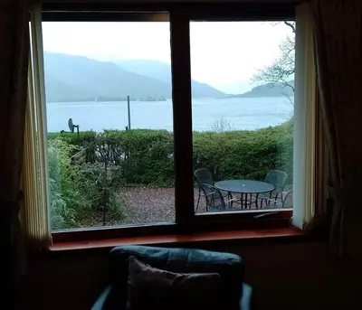 a window with a view of a table and a horse outside at Lochside Cottage Glencoe