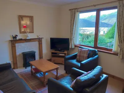 a living room with a couch and a fireplace at Lochside Cottage Glencoe
