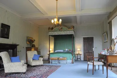 a bedroom with a bed and chairs and a chandelier at The South Wing in Acharn
