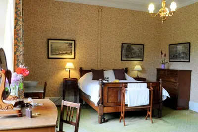 a bedroom with a bed and a table and chairs at The South Wing in Acharn