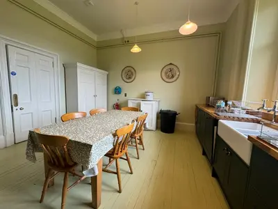 a kitchen with a table with chairs and a sink at The South Wing in Acharn