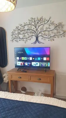a tv sitting on a wooden stand in a bedroom at Entire Spacious 3-Bed Family Home, City Centre, Free Parking, Garden in Glasgow