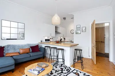 a living room with a couch and a kitchen at GuestReady - Modern 1BR in Edinburgh in Edinburgh