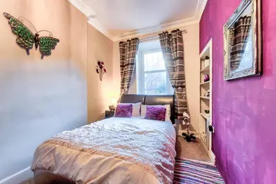 a pink bedroom with a bed with purple pillows at Edinburgh Drumdryan Central Apart in Edinburgh