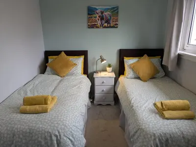 a bedroom with two beds with yellow pillows at Edinburgh Home from Home in Edinburgh