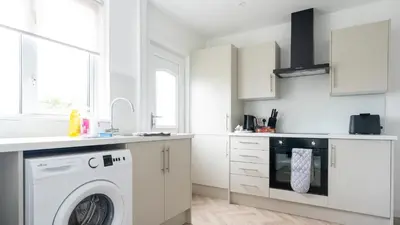 a white kitchen with a washing machine in it at Craigseaton House in Broxburn