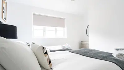 a white bedroom with a bed and a window at Craigseaton House in Broxburn