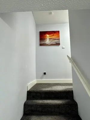 a stairway with a painting on a white wall at Superb Homestay in Cowlairs