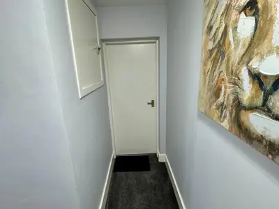 a hallway with a white door and a painting on the wall at Superb Homestay in Cowlairs