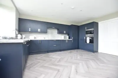 a kitchen with blue cabinets and a wooden floor at The Cliff Retreat in Wemyss Bay
