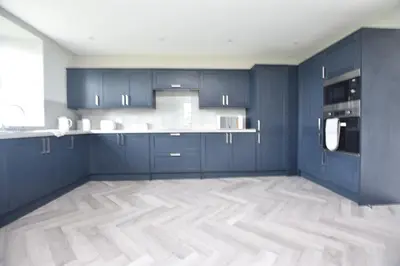 a kitchen with blue cabinets and a wooden floor at The Cliff Retreat in Wemyss Bay
