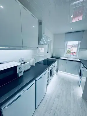 a kitchen with white cabinets and a black counter top at Modern 2 Bedroom with extra Loft Bedroom in Glasgow