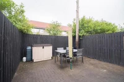 a patio with a table and chairs in front of a fence at Clydebank 2 Bedroom Home in Drumchapel