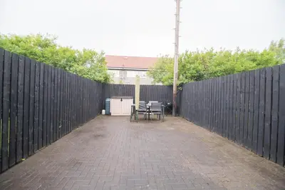 a patio with a fence and a table and chairs at Clydebank 2 Bedroom Home in Drumchapel
