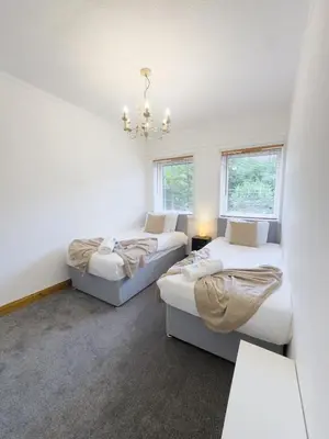 two beds in a room with two windows at Clydebank 2 Bedroom Home in Drumchapel
