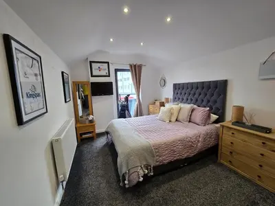 a bedroom with a king sized bed and a dresser at Central Portrush Townhouse available for Open Golf in Moffat