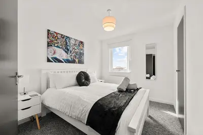 a white bedroom with a large bed and a window at Ochil View 30 mins to Edinburgh and Glasgow in Falkirk