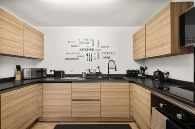 a kitchen with black counter tops and wooden cabinets at Ochil View 30 mins to Edinburgh and Glasgow in Falkirk