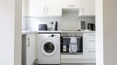 a white kitchen with a washing machine in it at Forbes House in Glasgow