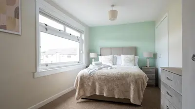 a bedroom with a bed with a large window at Tummel Place in Grangemouth