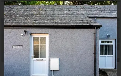 a gray house with two windows and a white door at Central Mews Free Wi-Fi-Parking-Contractors in Newton Stewart