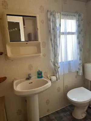 a bathroom with a sink and a toilet and a mirror at 27 Glenfinart Caravan Park in Dunoon