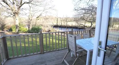 a porch with a table and a fence at Luxurious Riverside Lodge - 'The Ardle' in Crieff