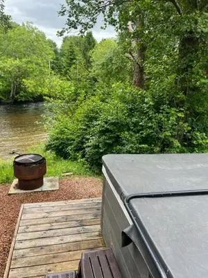 a wooden deck with a bbq and a barrel at Luxurious Riverside Lodge - 'The Ardle' in Crieff