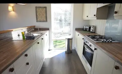 a kitchen with white cabinets and a stove top oven at Luxurious Riverside Lodge - 'The Ardle' in Crieff