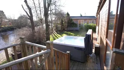 a hot tub sitting on the porch of a house at Luxurious Riverside Lodge - 'The Ardle' in Crieff