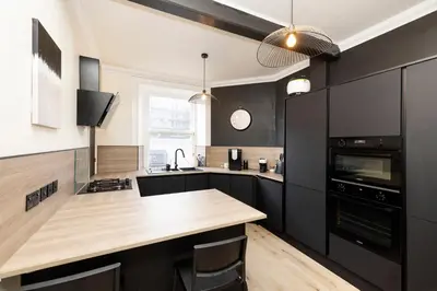 a kitchen with black cabinets and a wooden counter top at Elegant Apartment in the heart of Edinburgh in Edinburgh
