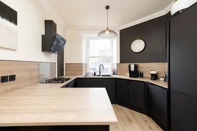 a kitchen with black cabinets and a clock on the wall at Elegant Apartment in the heart of Edinburgh in Edinburgh