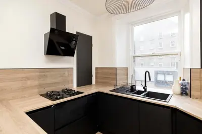 a kitchen with black cabinets and a sink and a window at Elegant Apartment in the heart of Edinburgh in Edinburgh