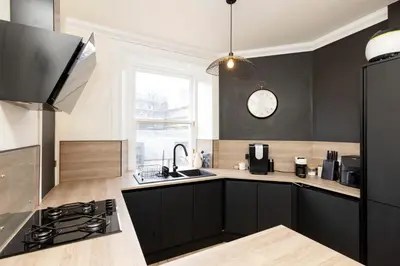 a kitchen with black cabinets and a clock on the wall at Elegant Apartment in the heart of Edinburgh in Edinburgh